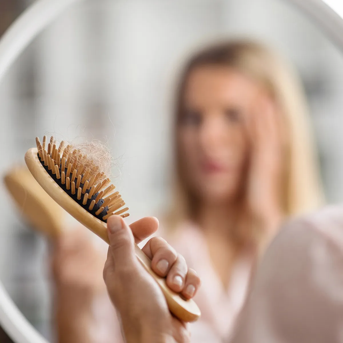 Woman noticing excessive hair shedding in her hairbrush, one of the first signs that something has changed with her hair